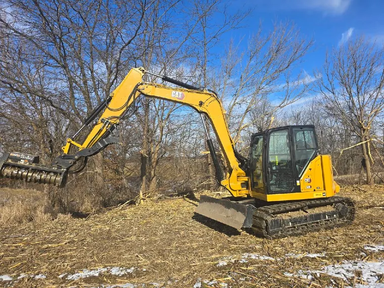 CAT 308 excavator with a forestry mulcher head clearing timber at a field edge in Brimfield, Illinois